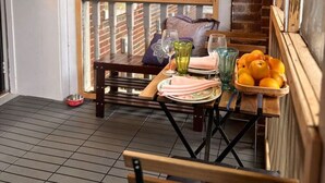 A balcony with a table set for two, a chair, a bowl for a pet, and a basket of oranges. - Ground floor flat at Virginia Highlands (Atlanta)