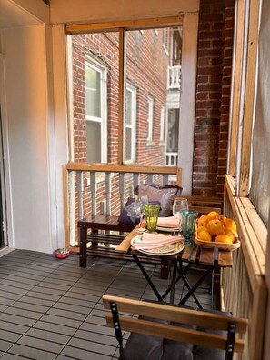 A balcony with a table set for two, a chair, a bowl for a pet, and a basket of oranges. - Ground floor flat at Virginia Highlands (Atlanta)