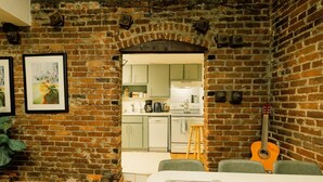 A kitchen with a brick wall, a guitar, and a dining area with a sink. - Ground floor flat at Virginia Highlands (Atlanta)