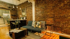 A living room with a brick wall, a sofa, a coffee table, and a side table. - Ground floor flat at Virginia Highlands (Atlanta)