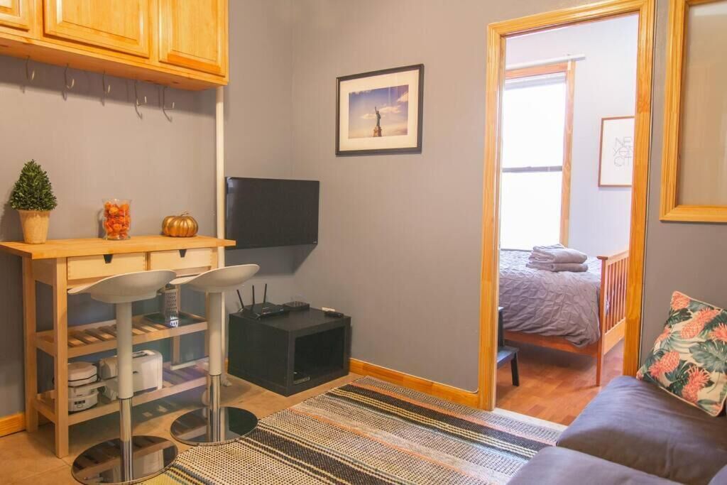 A compact room with a bed, a small desk, a TV, and a door leading to another room.