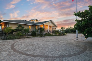 A two-story house with a covered porch, a paved driveway, and a flagpole.