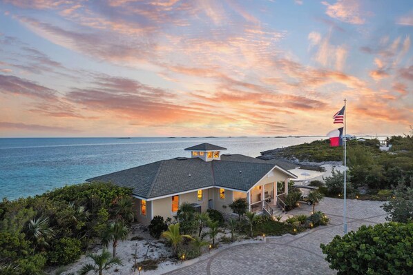 A beachfront property with a house, a flag, and a view of the ocean.