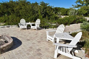 An outdoor patio with Adirondack chairs and a fire pit.