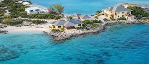 Una propiedad costera con varias casas, una playa y aguas azules cristalinas.