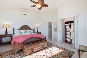 A bedroom with a wooden bed, two bedside tables with lamps, a ceiling fan, a wardrobe, and a patterned carpet. - Secluded Private Beachfront Villa on Staniel Cay in Exumas Bahamas (Staniel Cay)