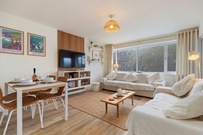 A modern living room with a dining area, white furniture, a flat-screen TV, and large windows. - 3 Monkstone Court - Close to Village and Beach (Saundersfoot)