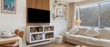 Un salon avec un canapé, une table basse, un téléviseur et une bibliothèque.
