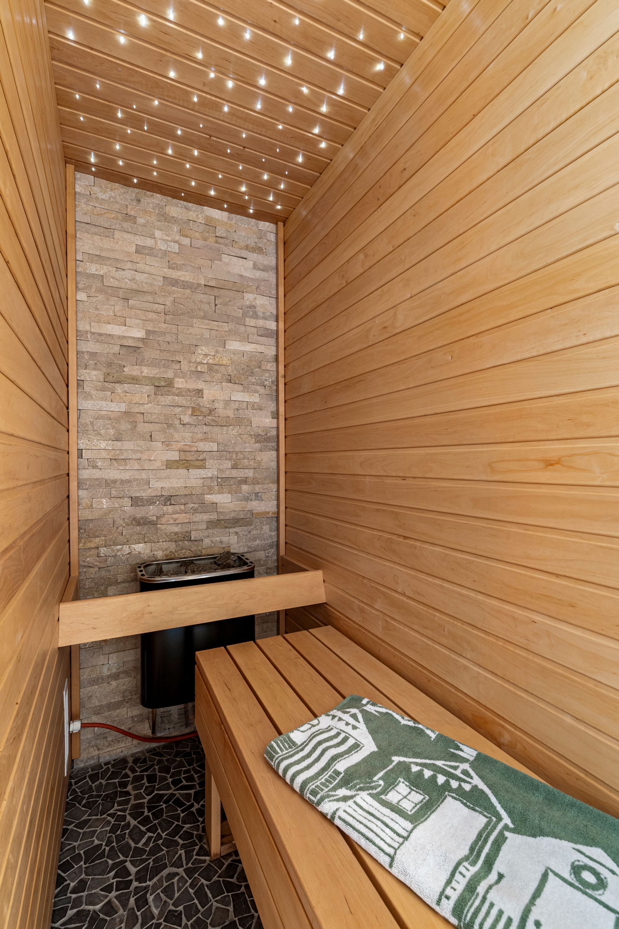 Un sauna avec des murs en bois, un banc et un mur en pierre.