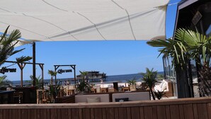 Un restaurante frente a la playa con terraza, vista al mar y una cubierta de madera.