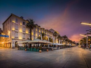 Ein Hotel mit Außenbereich, Palmen und einem Sonnenuntergangshimmel.