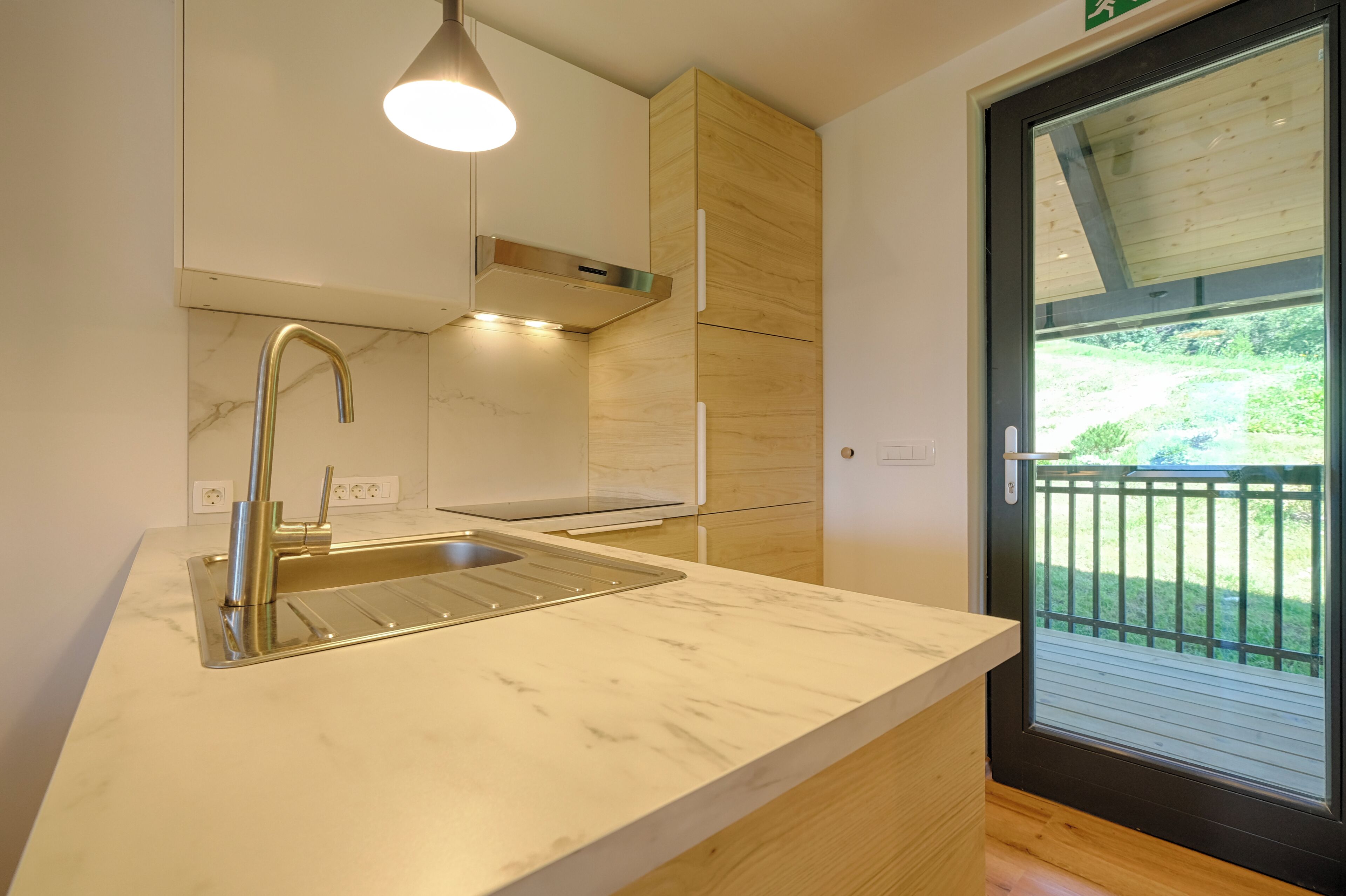 A modern kitchen with a marble countertop, stainless steel sink, and wooden cabinets.