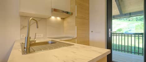 A modern kitchen with a marble countertop, stainless steel sink, and wooden cabinets.