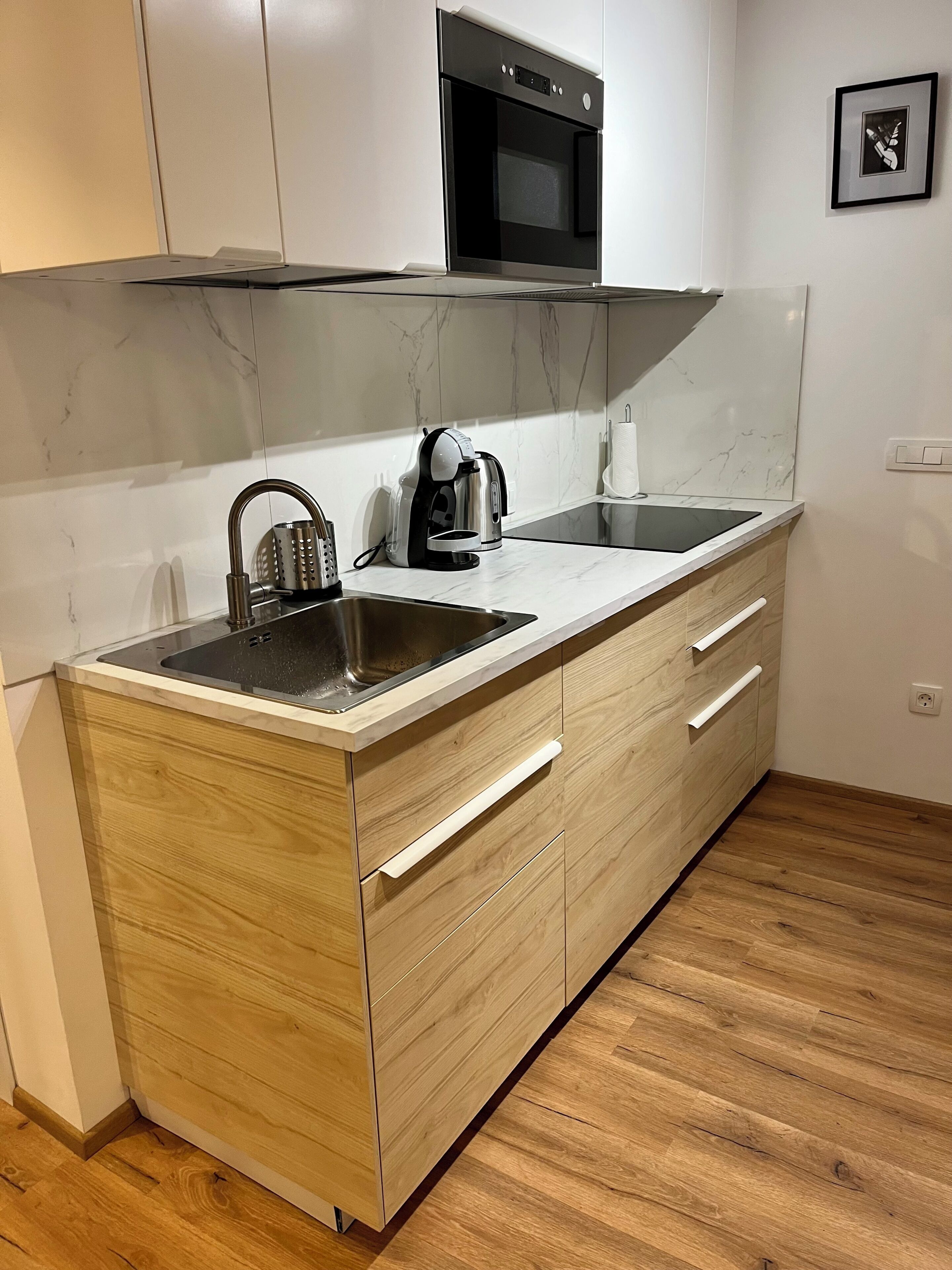 A modern kitchen with a built-in oven, a sink, and a coffee maker.