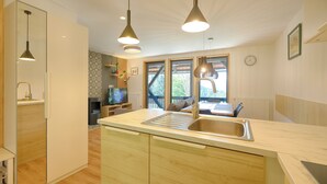 A modern kitchen with a central island, pendant lights, and a view of the outdoors. - Apartments pri fencu (Jesenice)