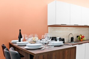 Une cuisine moderne avec un îlot central en bois, des meubles blancs et un panier de fruits.