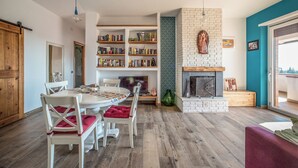 Una sala de estar con chimenea, estanterías, una mesa de comedor con sillas y un televisor.