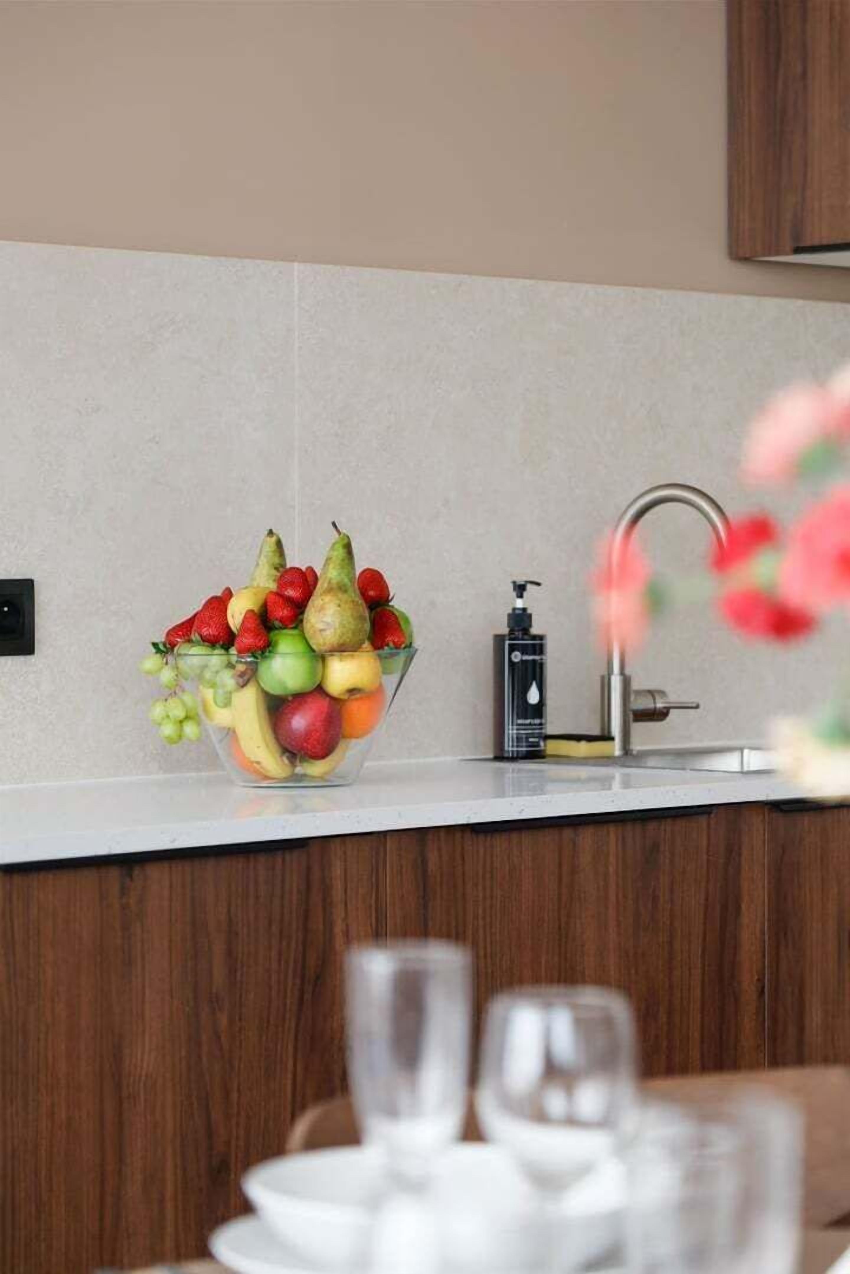A kitchen with a fruit bowl, a faucet, and a soap dispenser.