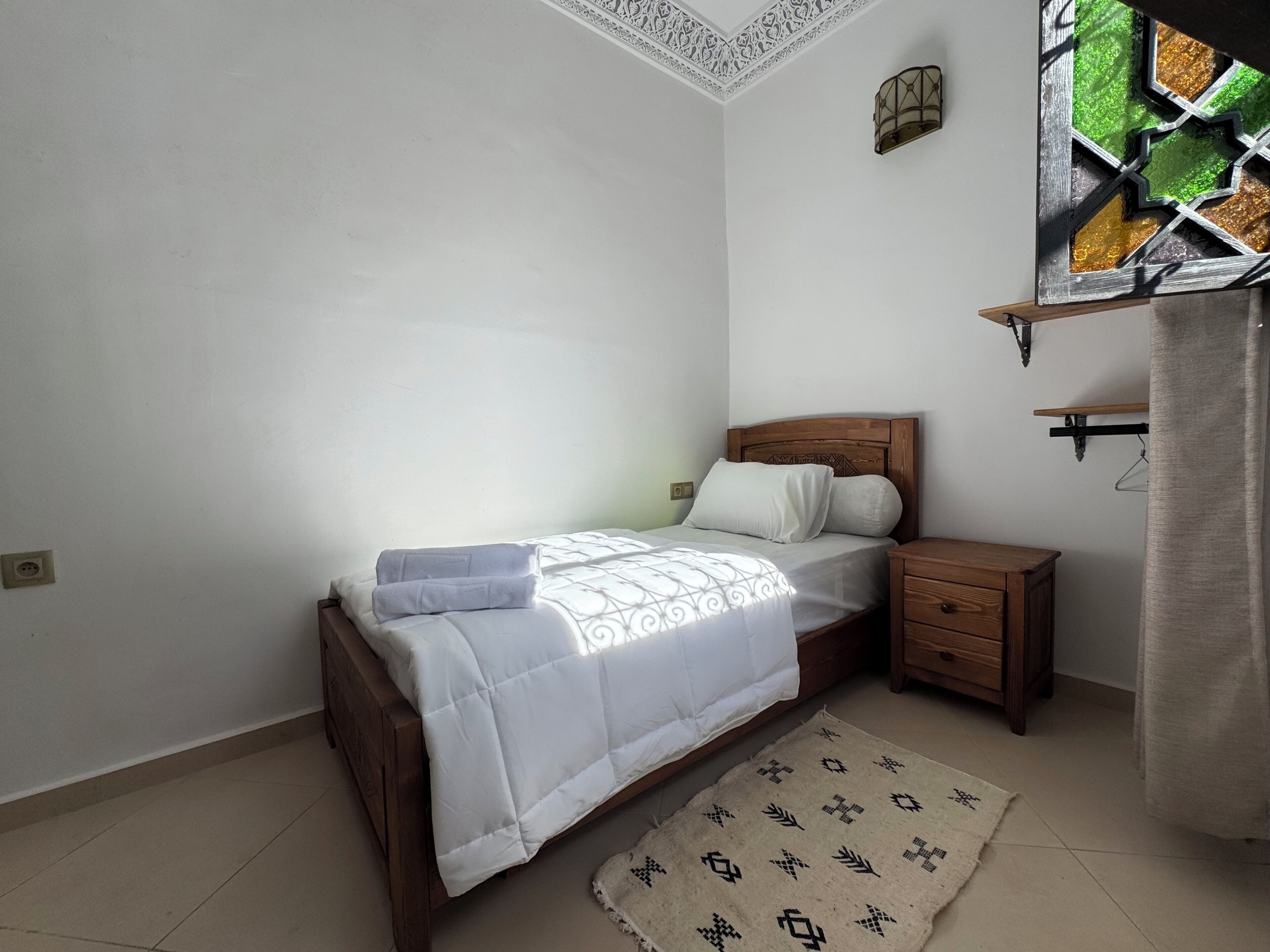 Un dormitorio con cama, mesita de noche y una cómoda de madera.