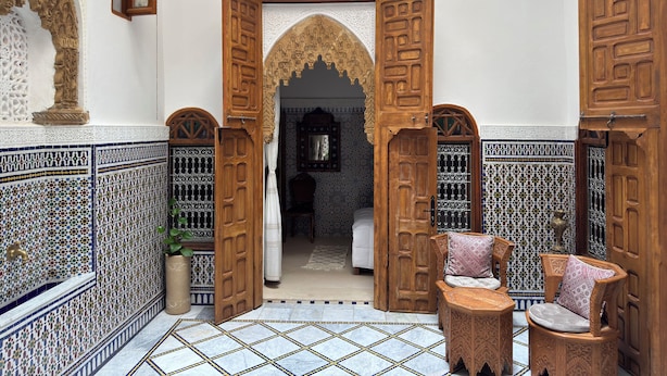 An interior with open wooden doors, a tiled floor, and a hanging light fixture.