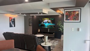 Un soggiorno moderno con un divano, una TV, opere d'arte e una pianta decorativa.