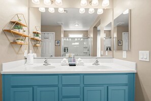 A bathroom with a double sink, two towel racks, a mirror, and a geometric shelf unit. - Desert Sky Escape in Marana (Marana)