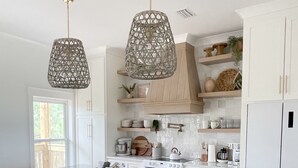 A modern kitchen with a central island, bar stools, pendant lights, and white cabinetry. - Lux home, walkable to priv beach, near marina, golf in Gulf Shores Fort Morgan (Gulf Shores)
