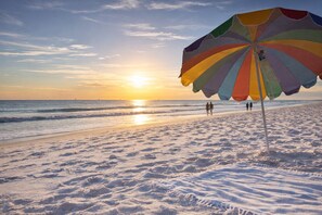A beach with a colorful umbrella and footprints in the sand. - Lux home, walkable to priv beach, near marina, golf in Gulf Shores Fort Morgan (Gulf Shores)