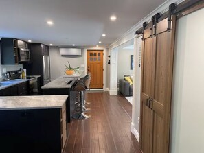 A modern kitchen with dark cabinetry, a central island, and a sliding barn-style door.