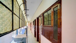 A corridor with patterned windows, a bench, and a door. - Hotel O Isbt Sector 43 Bus Terminal (Chandigarh)