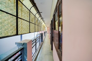 A corridor with patterned glass windows, a metal railing, and a tiled floor. - Hotel O Isbt Sector 43 Bus Terminal (Chandigarh)