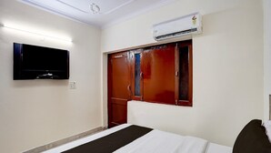 A hotel room with a bed, a flat-screen TV mounted on the wall, and an air conditioning unit above the door. - Hotel O Isbt Sector 43 Bus Terminal (Chandigarh)