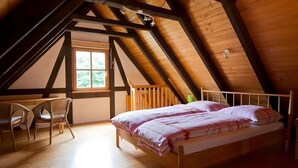 Un dormitorio con techo inclinado, una cama, un escritorio y una silla.