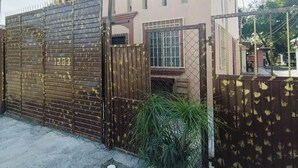 Un edificio de dos pisos con una entrada porticada, el número '1283' visible en la puerta, y una planta pequeña en primer plano.