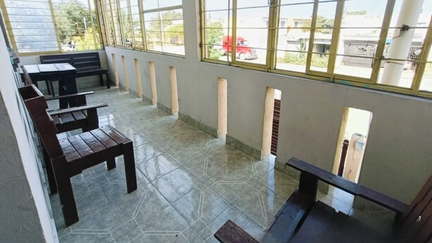 Una habitación con amplios ventanales, suelo de baldosas y bancos de madera.