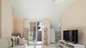 Un salon moderne avec un canapé, un téléviseur et un balcon agrémenté de rideaux.
