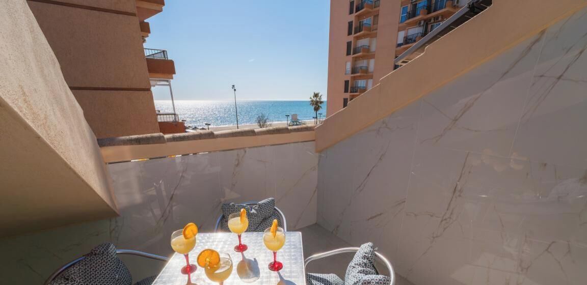 Ein Balkon mit Tisch, gedeckt für Getränke, mit Blick auf Strand und Meer.