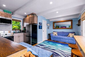 A compact kitchen with modern appliances, a dining area with a wooden table, and a blue sofa with cushions. - Perfect Ptown Stay, Dogs Welcome, Walk Everywhere (Provincetown)