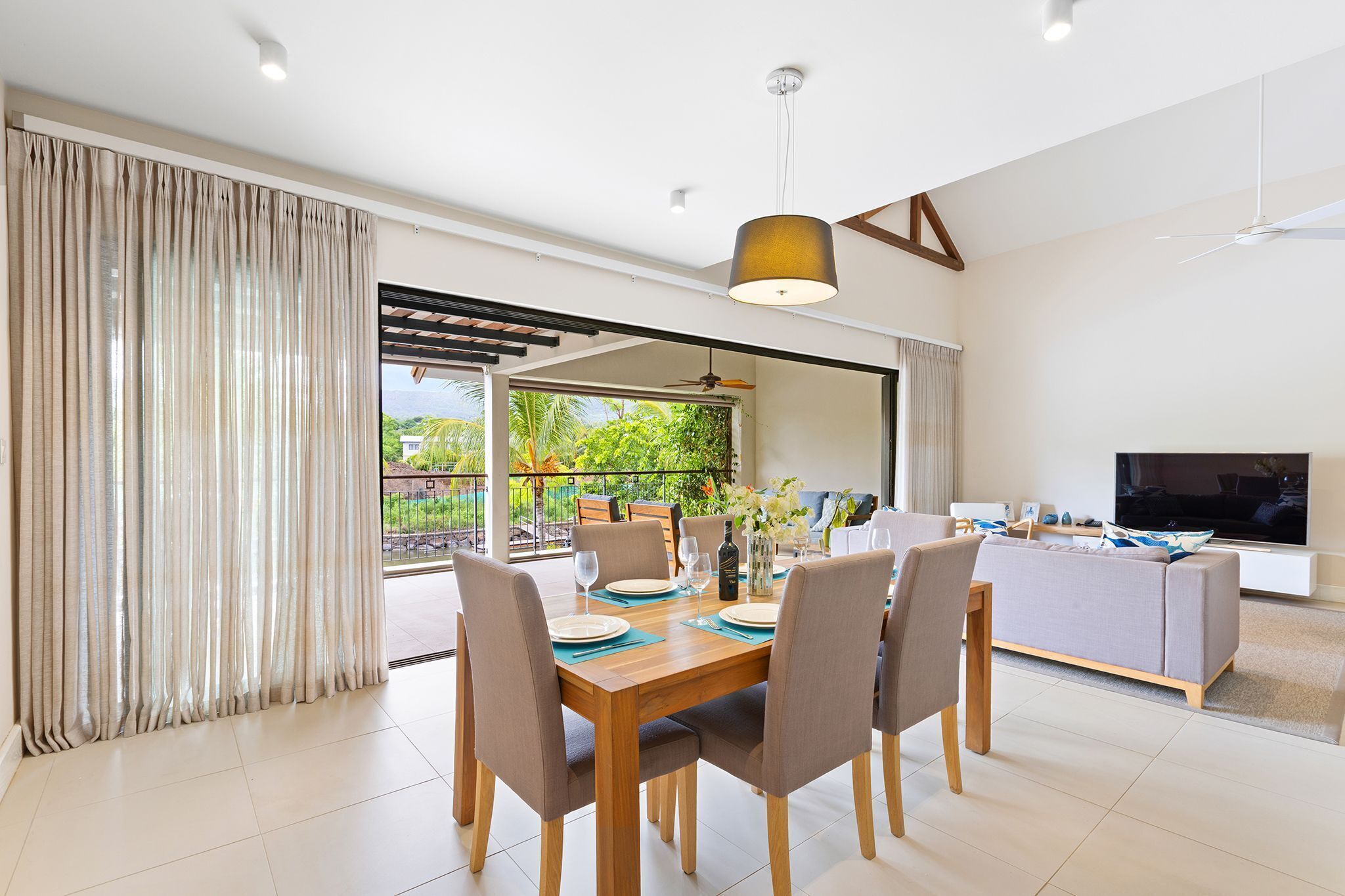 Una sala de estar moderna con comedor, ventanas amplias y un televisor de pantalla plana.