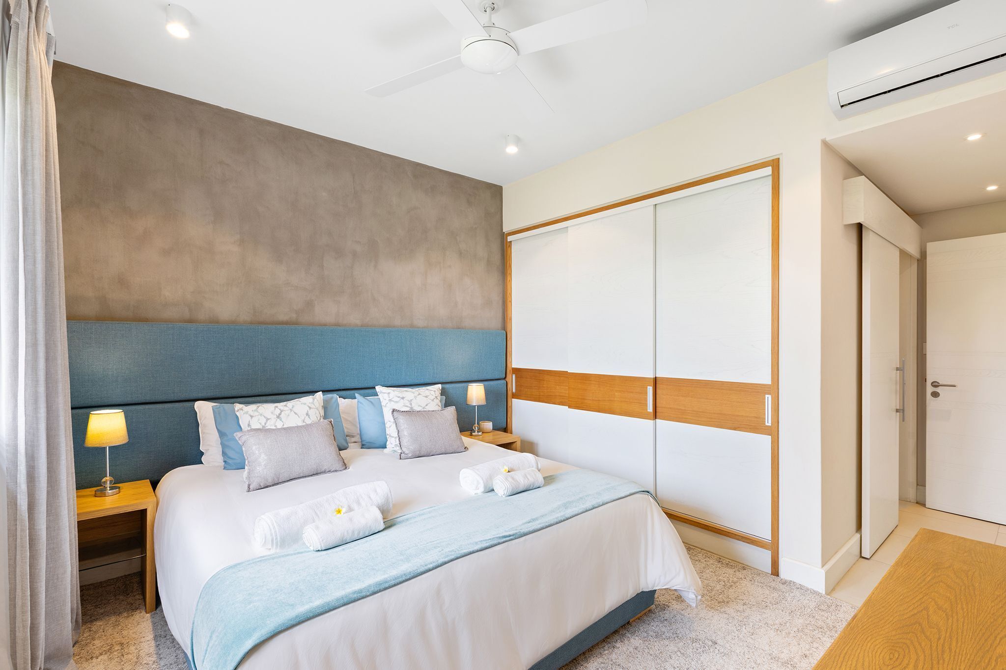 Une chambre d’hôtel équipée d’un lit, de tables de chevet, d’un ventilateur de plafond, d’un appareil de climatisation et d’une armoire.