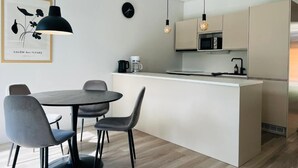A modern kitchen with a central island, pendant lights, and a framed artwork on the wall. - Modern 3BR House with Sauna & Parking (Vantaa)