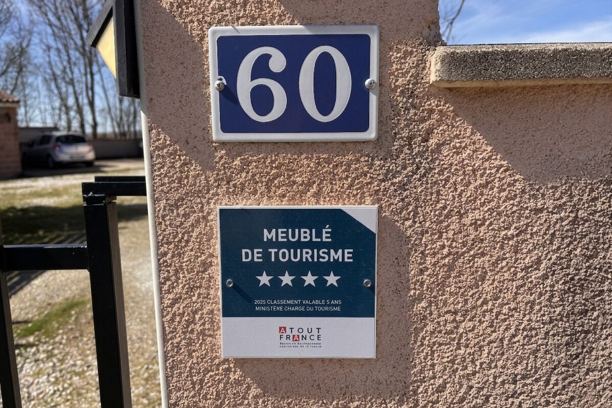 A wall with a blue sign displaying the number 60 and a smaller sign below it indicating a tourism award.