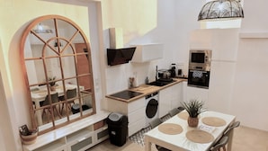 A compact kitchen with a dining area, a large mirror, and built-in appliances. - Loft with Private Pool, Jacuzzi, AC & Garden – Peaceful Countryside (Saint-Grégoire)