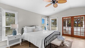 A bedroom with a bed, bedside tables, a ceiling fan, and a view through a glass door. - Cozy home in Sarasota (Sarasota)