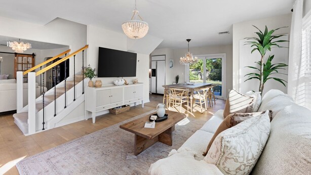 A spacious living room with a staircase, a dining area, and a large TV. - Cozy home in Sarasota (Sarasota)