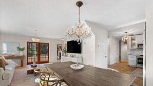 A spacious living area with a wooden dining table, a chandelier, and a kitchen in the background. - Cozy home in Sarasota (Sarasota)