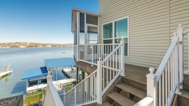 En ejendom ved vandet med balkon, pool og trappe op til øvre etage.