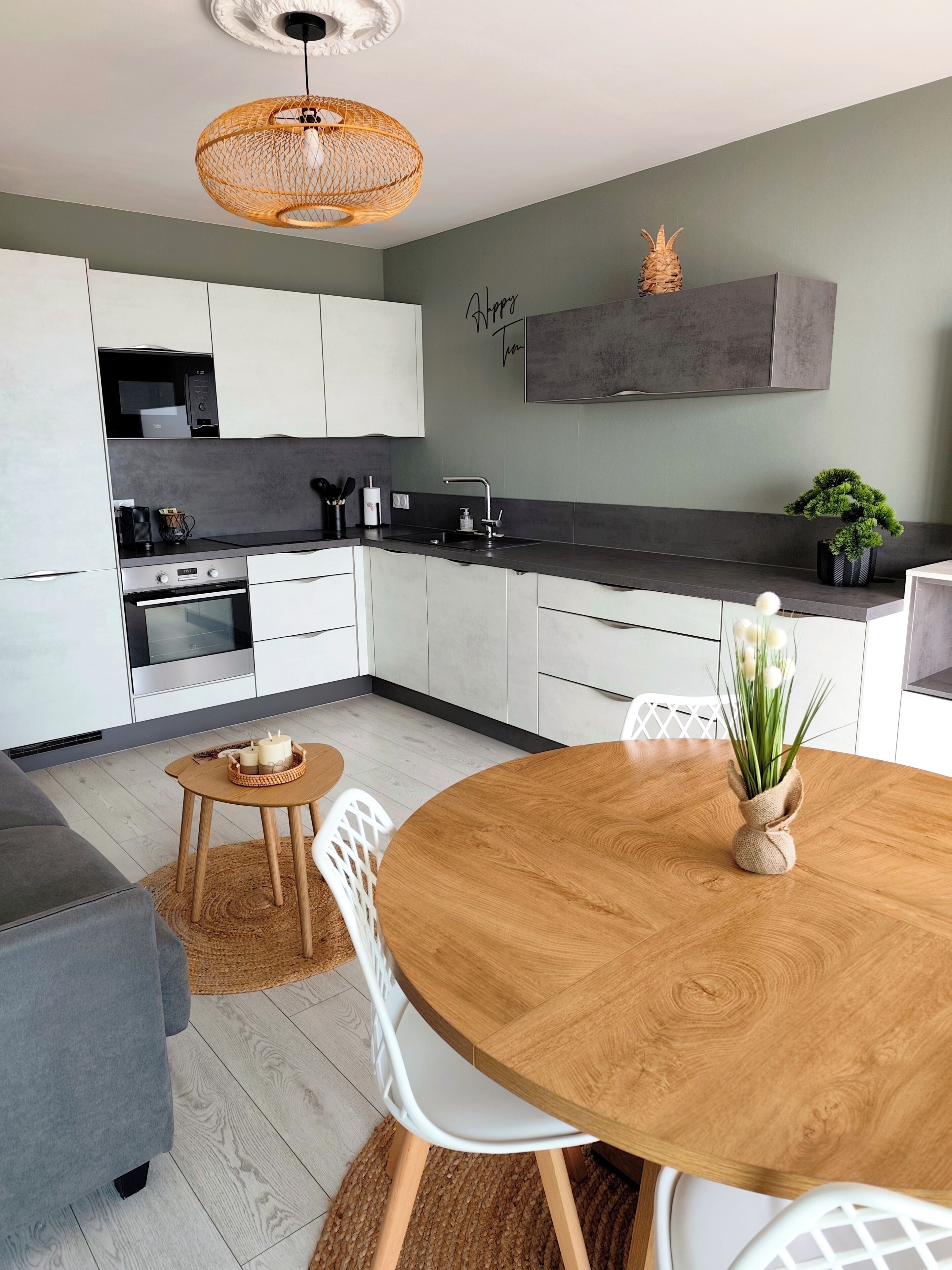 Eine moderne Küche mit weißen Schränken, einem Holztisch und einer Pendelleuchte.