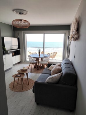 A modern living space with a dining area, sofa, and a view of the beach. - Le 8ème Ciel - Panoramic sea view - Balcony - Wifi (Saint-Jean-de-Monts)