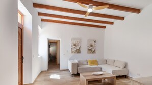 Un salon spacieux avec un plafond en bois, un canapé, une table basse et deux œuvres d’art murales aux motifs floraux.